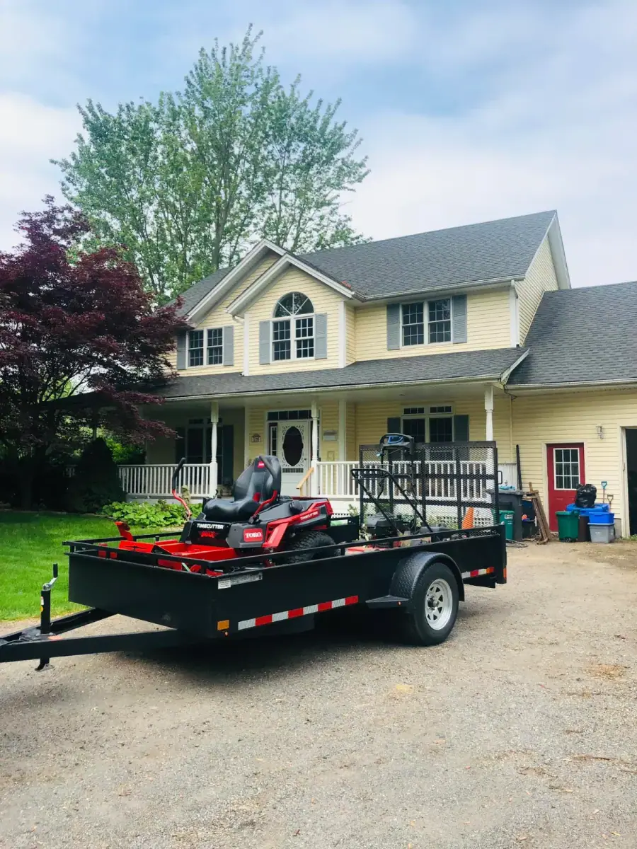 Trailer with zero-turn mower parked on a residential driveway